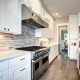 A high end kitchen with stainless steel appliances and white cabinets